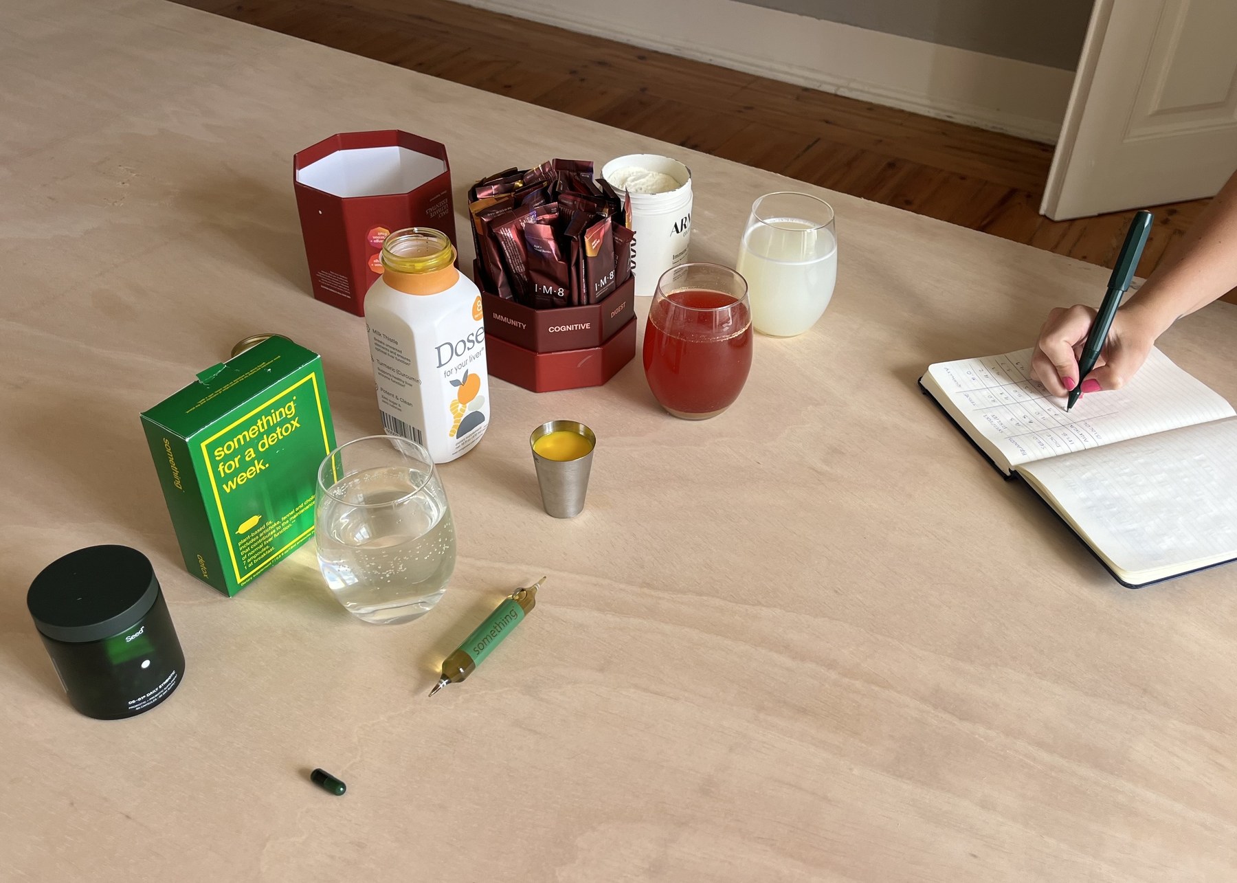 Filipa's testing setup with supplements laid out and a handwritten tasting notebook